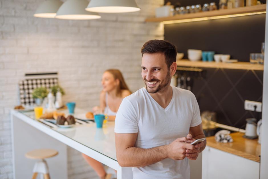 Das Leben im Smart Home. Bild: shutterstock.com/bbernard/508421383 Junger Mann freut sich in einem Smart Home zu Wohnen